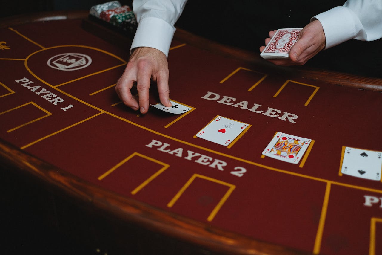 A casino dealer distributes playing cards at a poker table, ready for a game.